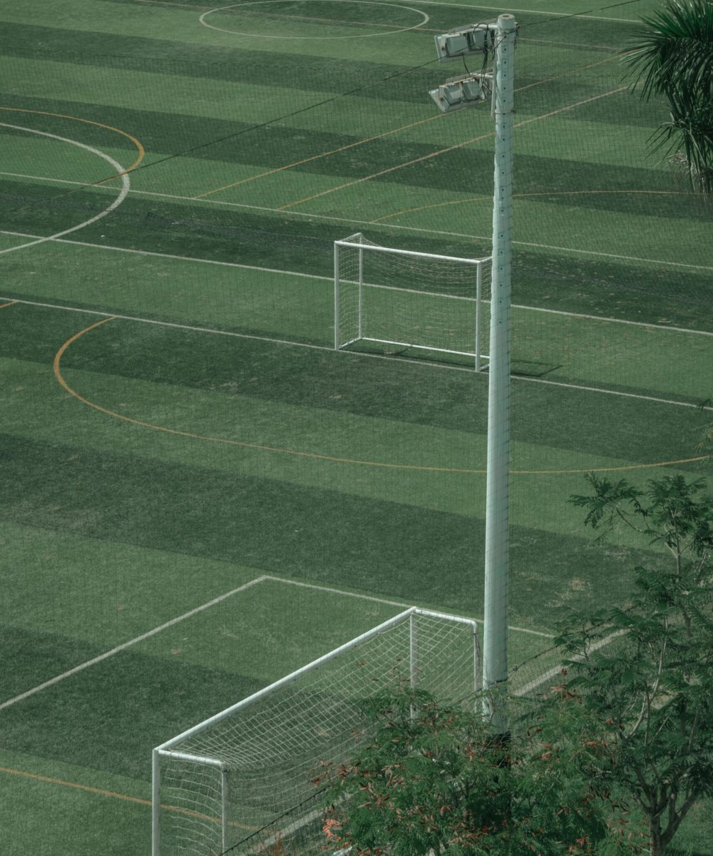 A detailed aerial shot of an empty soccer field showcasing multiple goals and green turf.